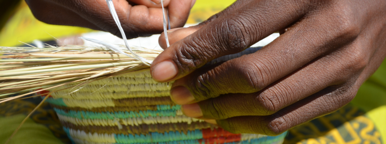 Woman's hand weaving brightly colored basket