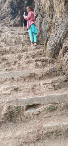 Nepalese woman climbing terraced rocky trail in rural Nepal